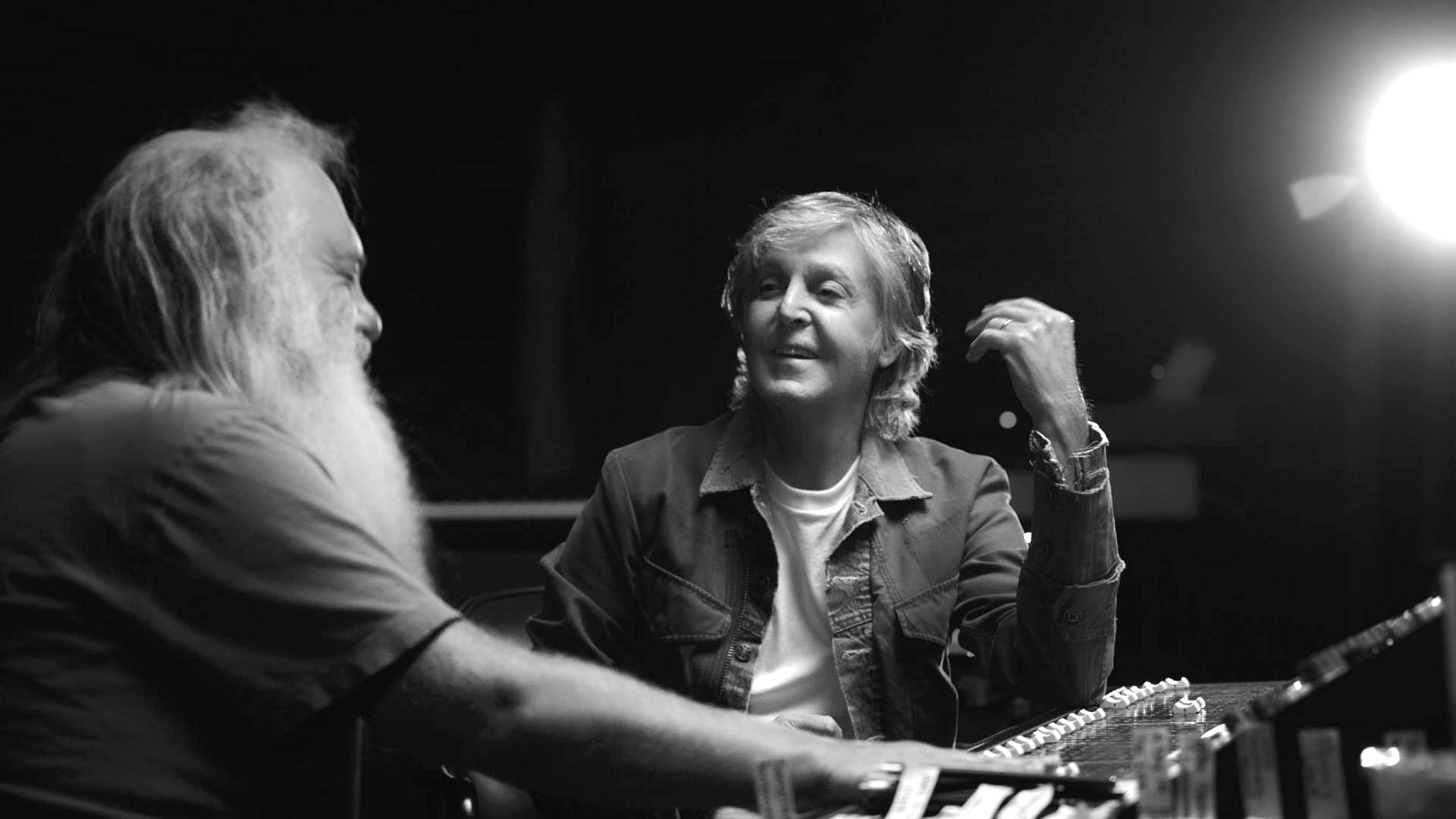 Black and white photo of Paul at a mixing desk talking to Rick Rubin