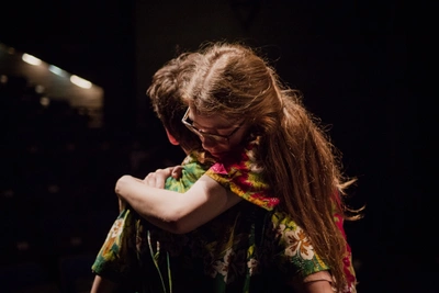 Photograph of Ben Kulvichit and Clara Potter-Sweet hugging on stage 