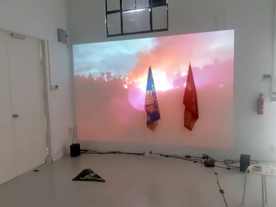 Thamis worn by the refugee women hang against a backdrop of footage collected by the artist.