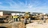 Crew of construction workers wearing high visibility vests and talking at a job site with tractors in the background