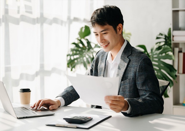 Man using laptop and looking at papers