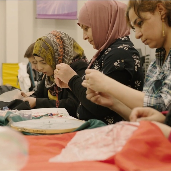 Women working on embroidery projects around a table