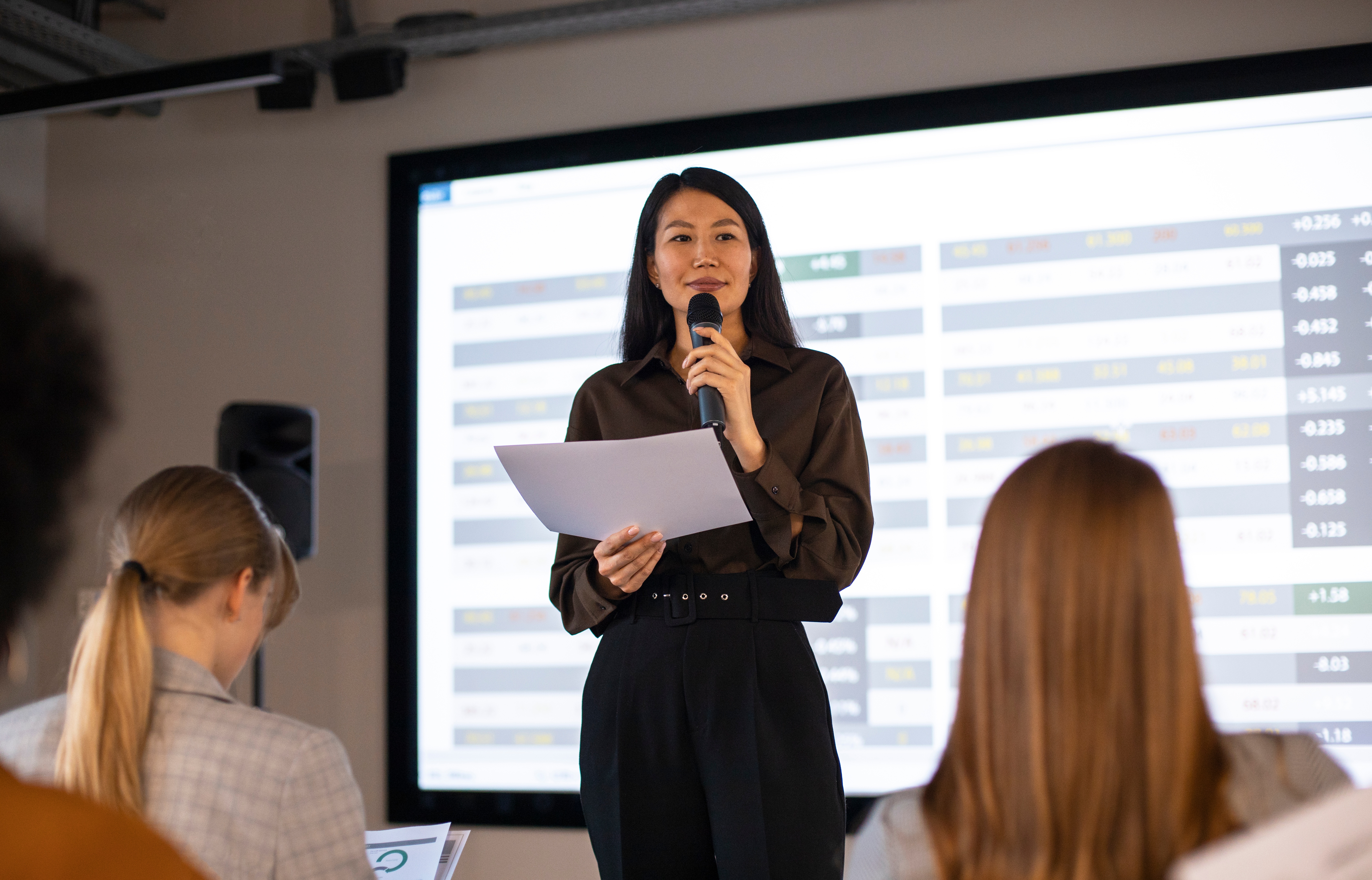 Seorang wanita dengan skill public speaking yang baik sedang presentasi di kantor.