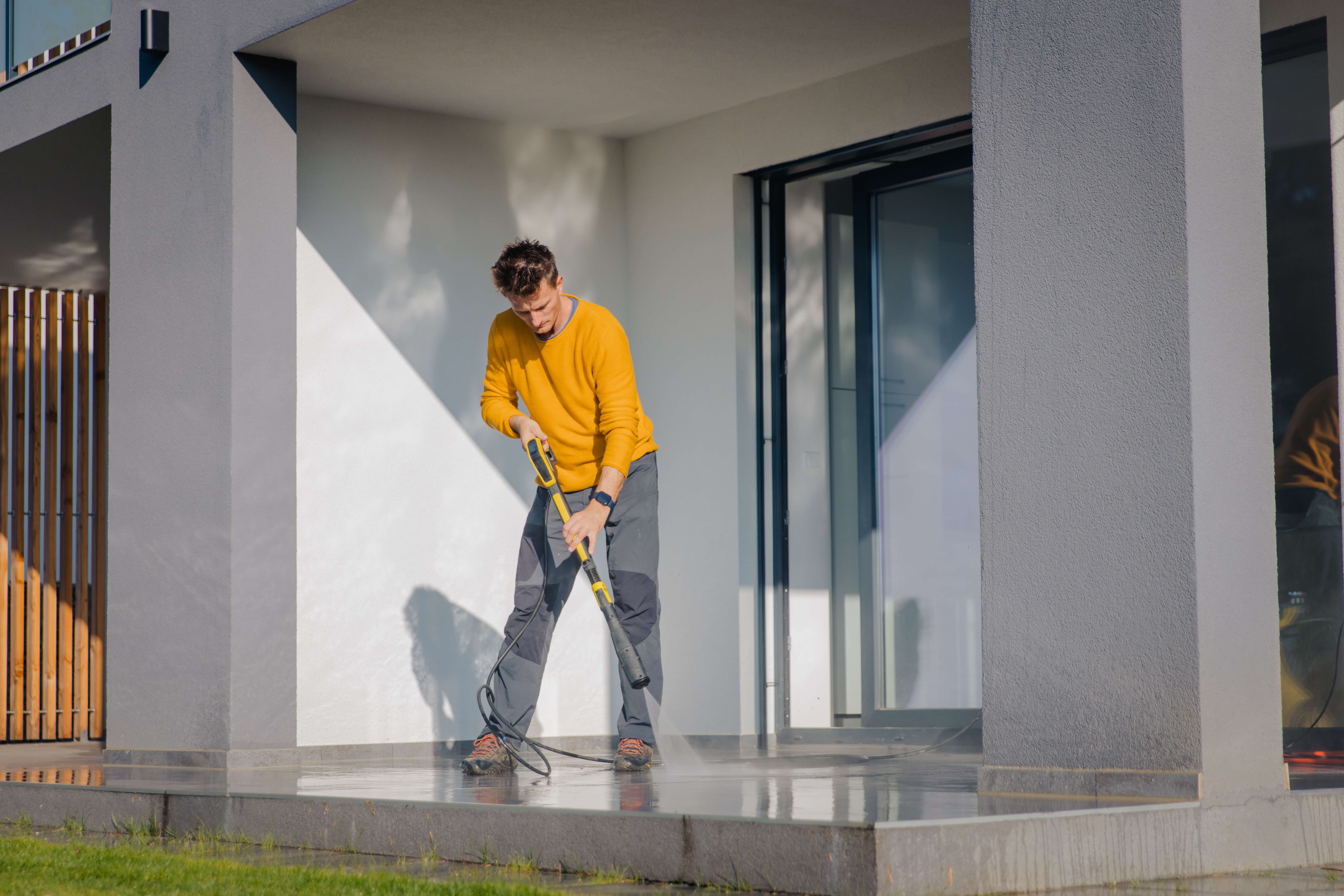  Man cleaning the patio of the apartment with high pressure cleaner