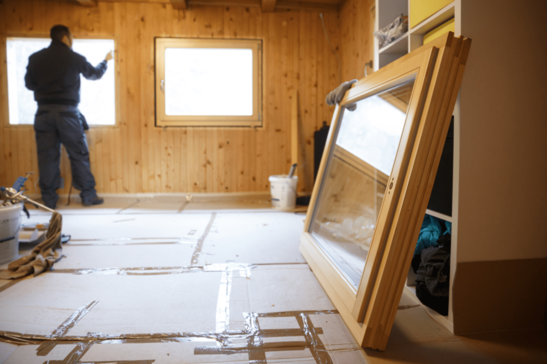 man fitting window on wooden wall