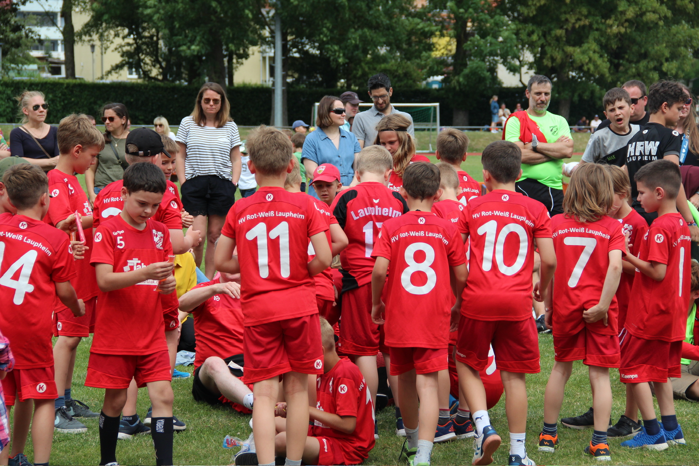 Viele Kinder in roten HRW-Trikots draußen auf einem Sportplatz