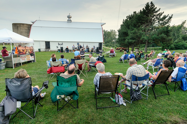 An event takes place on the lawn outside of a winery's tasting room.