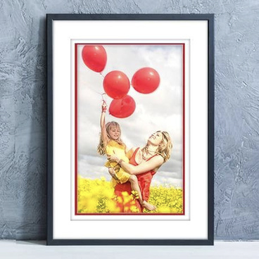 framed print of child holding balloon resting against a wall