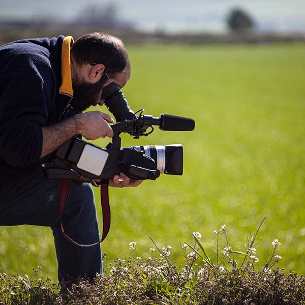 Cameraman filming outside in a field