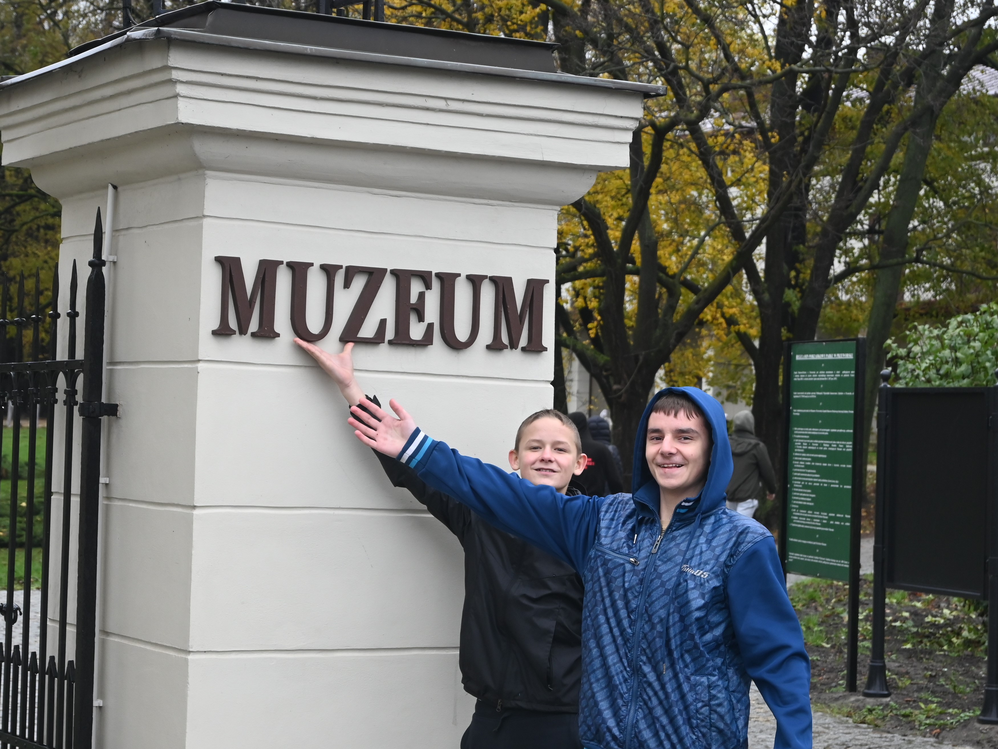 20 listopada - nasza wycieczka do Przeworska i Rzeszowa  | Dwóch chłopców wskazuje ręką napis MUZEUM mieszczący się na białym, masywnym filarze..JPG