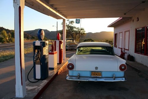 A 1950's style car parked next to retro gas pumps