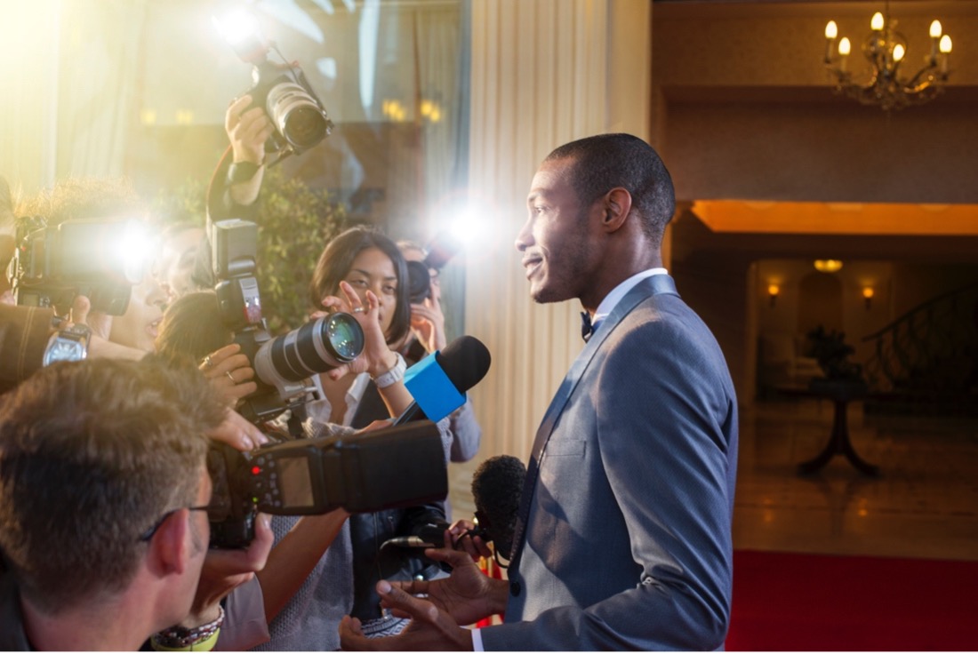 Man speaking to reporters on the red carpet of a film premiere.jpg