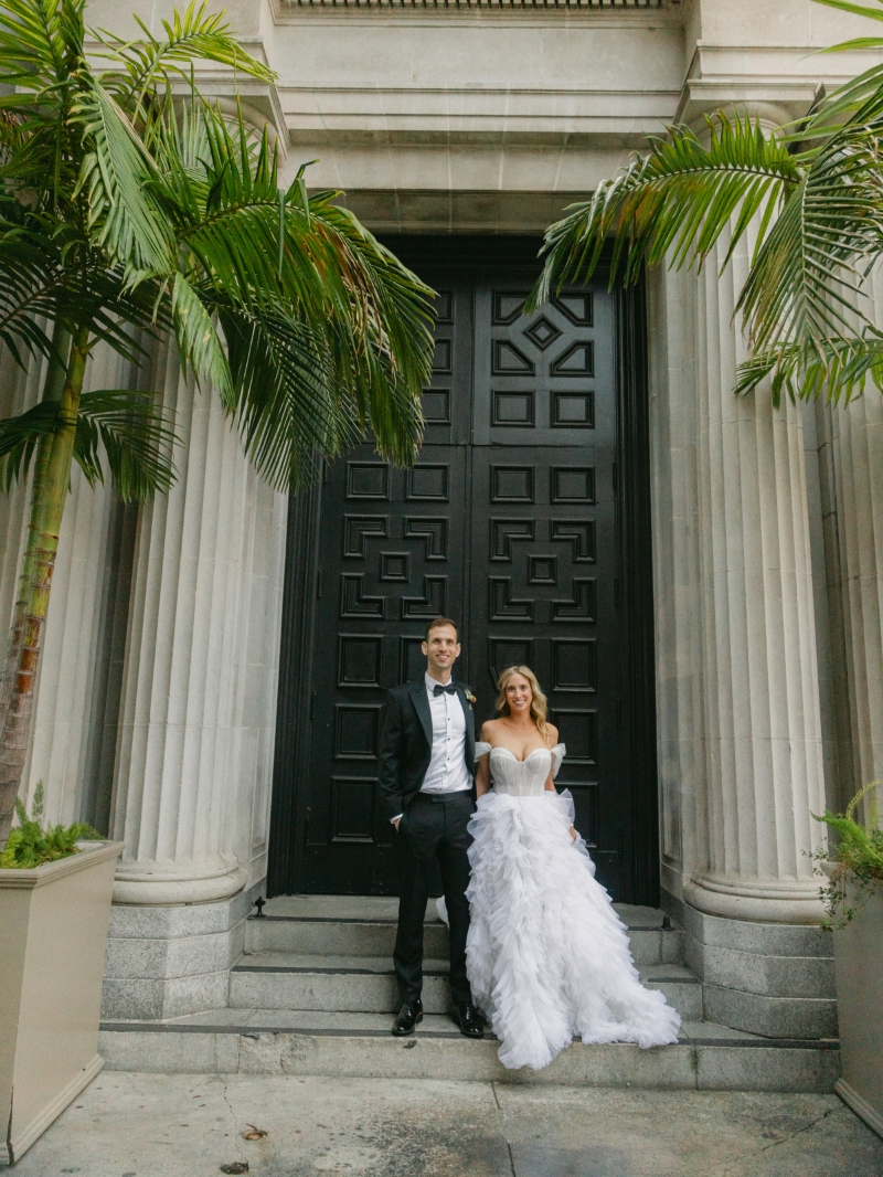 a bride and groom standing in front of the Vibiana cathedral front entrance doors in Downtown Los Angeles after their wedding ceremony