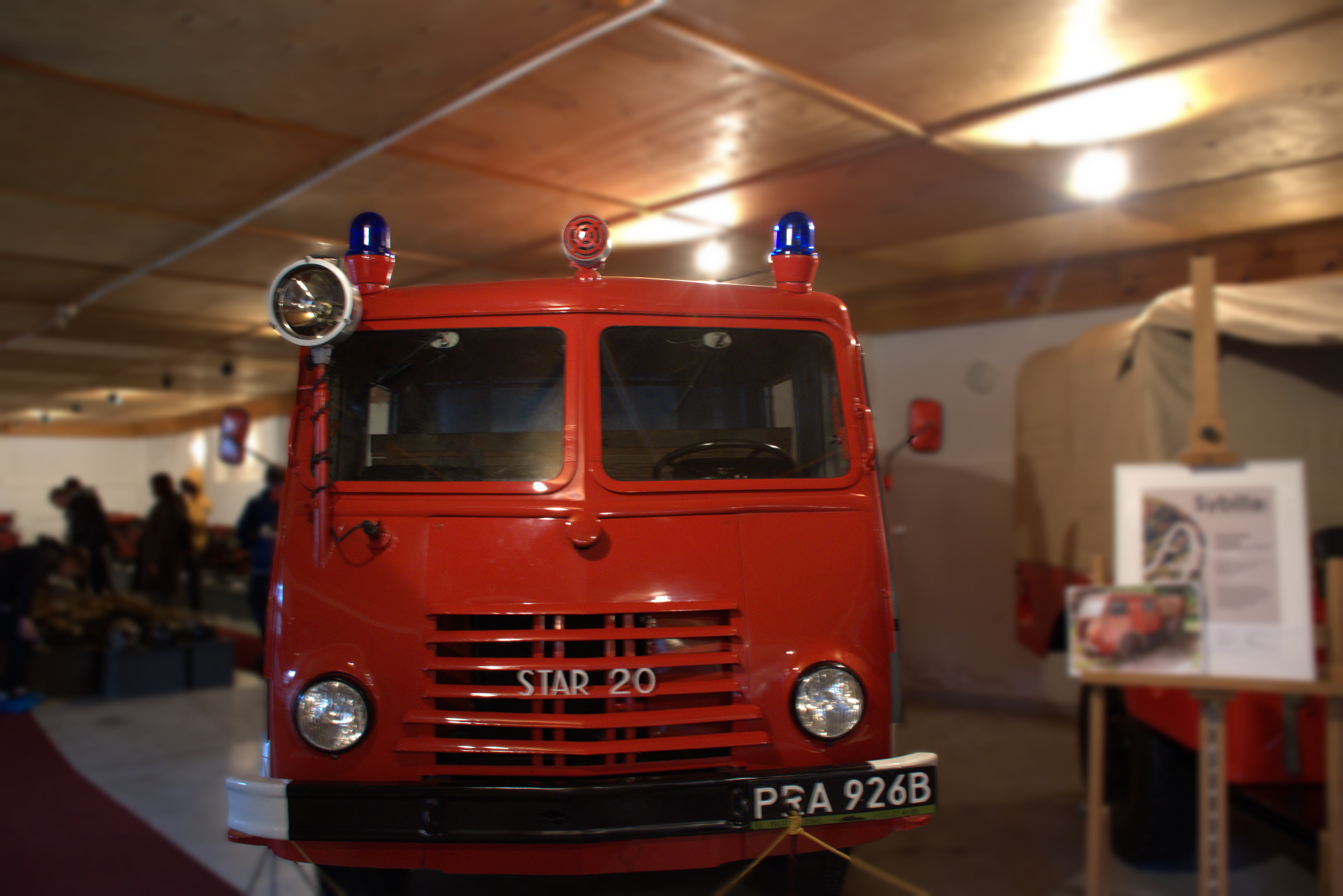 20 listopada - nasza wycieczka do Przeworska i Rzeszowa  | Czerwony, zabytkowy wóż strażacki widziany od przodu. W tle wnętrze hali muzeum..jpg