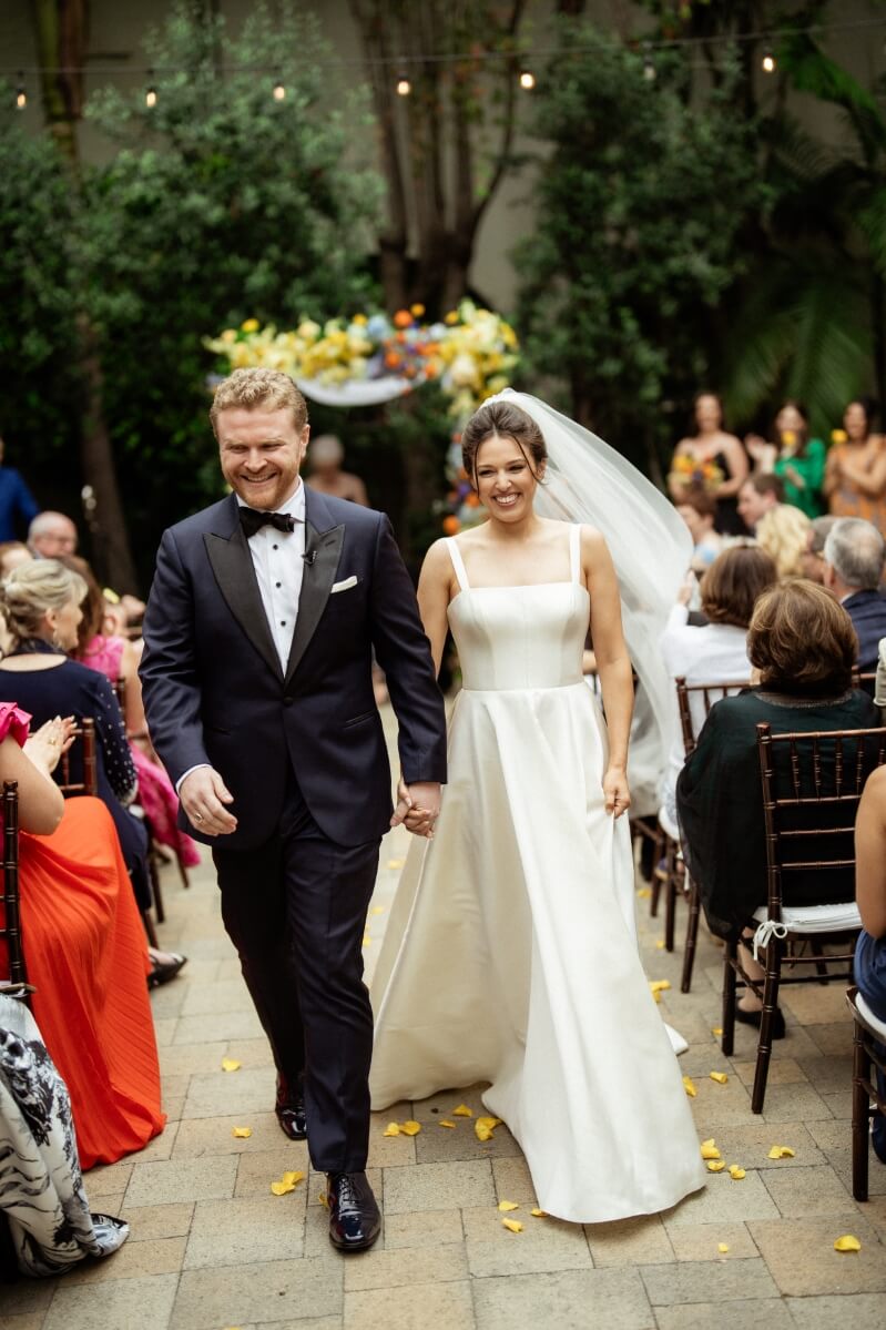 bride and groom smiling down aisle