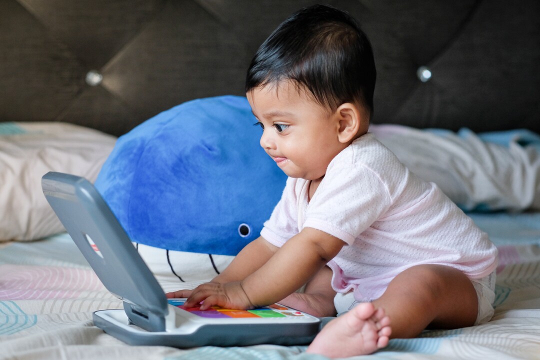 Baby playing on a toy laptop